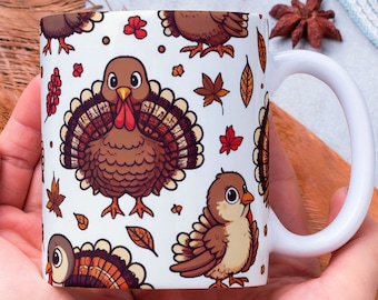 May include: White ceramic mug with a Thanksgiving-themed design featuring brown turkeys and red and brown leaves. The mug is being held by a person's hands.