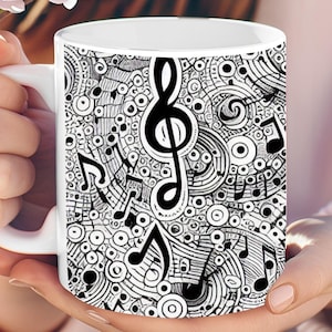 May include: White ceramic mug featuring a black and white musical design. The design includes musical notes, treble clefs, and abstract circular patterns. The mug is held in a person's hands, with a blurred background of pink flowers.