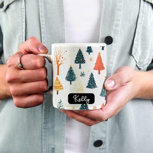 Puede incluir: Taza de cer&aacute;mica blanca con un patr&oacute;n de &aacute;rbol de Navidad y el nombre "Kelly" en la parte delantera.
