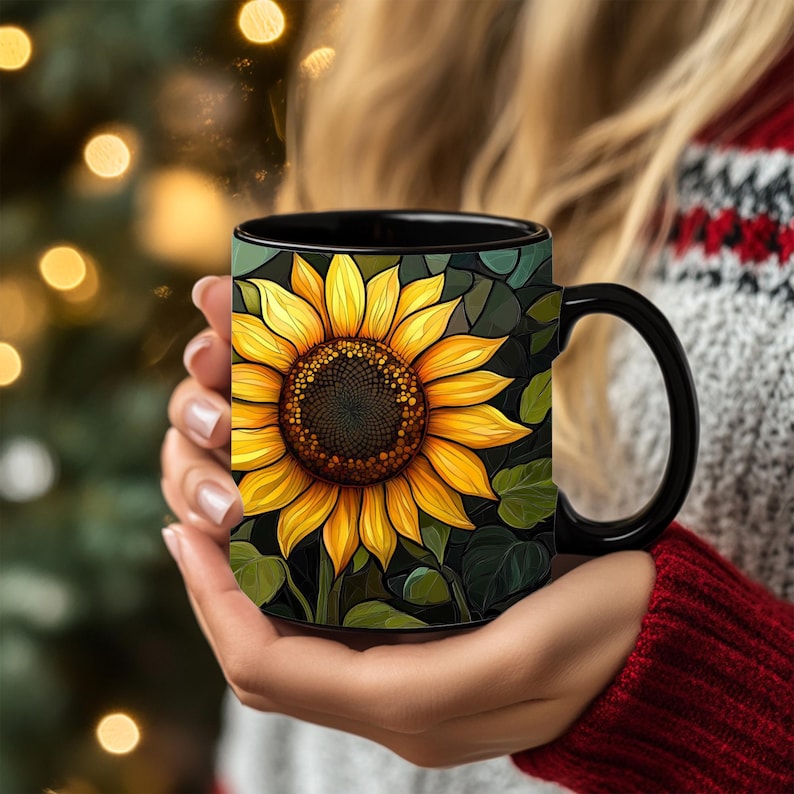 May include: Black coffee mug with a sunflower design. The sunflower is yellow with a dark brown center and green leaves.