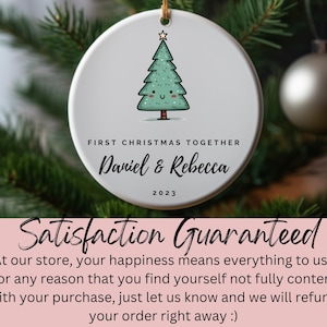 Peut inclure: Ornement de No&euml;l en c&eacute;ramique blanche avec un sapin de No&euml;l dessin&eacute; en vert et un visage souriant. L'ornement porte l'inscription "Premier No&euml;l Ensemble Daniel & Rebecca 2023".