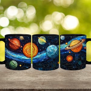 Op de afbeelding: Drie zwarte mokken met een mozaïekontwerp van planeten en sterren. De mokken zijn in een rij van links naar rechts gerangschikt. De eerste mok heeft een rode planeet met ringen, een gele planeet met ringen en een groene planeet. De tweede mok heeft een blauwe planeet met ringen, een gele planeet met ringen en een groene planeet. De derde mok heeft een rode planeet met ringen, een gele planeet met ringen en een groene planeet.