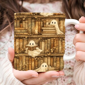 May include: A white ceramic mug featuring a wrap-around illustration of brown wooden bookshelves filled with old books and three small white ghosts. One ghost peeks from behind a book, another reads a book, and the third rests on a shelf.