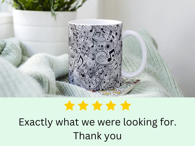 May include: White ceramic mug with a black and white design of musical notes and swirls. The mug has a handle and is sitting on a light green knitted blanket.