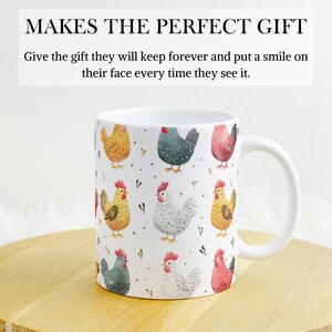 May include: White ceramic mug with a colorful pattern of chickens. The chickens are illustrated in a watercolor style with shades of yellow, red, gray, and white. The mug has a black handle.