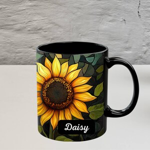 May include: Black coffee mug with a sunflower design and the word "Daisy" printed on the bottom.
