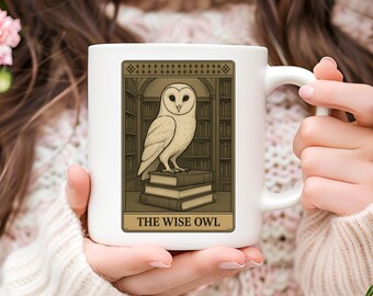 May include: White ceramic mug with an illustration of an owl on books, set against a library background. The design is framed with the text "THE WISE OWL" at the bottom. The mug has a curved handle. The design is in shades of brown and beige.