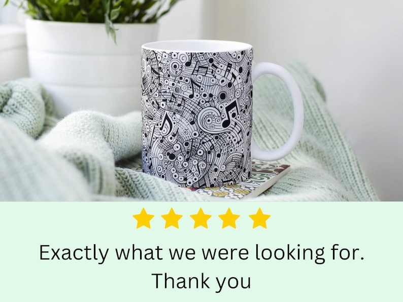 Puede incluir: Taza de cer&aacute;mica blanca con un dise&ntilde;o en blanco y negro de notas musicales y remolinos. La taza tiene un asa y est&aacute; sentada sobre una manta de punto verde claro.