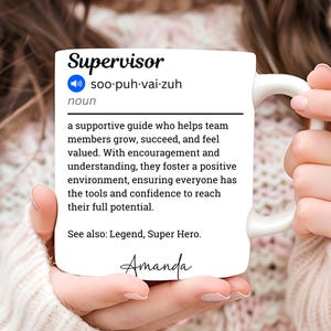 May include: White ceramic mug with the definition of "Supervisor" printed in black. The definition includes the pronunciation, a description of the role, and the name "Amanda" in script. The mug is held by a person.