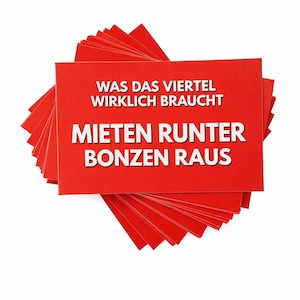 Könnte beinhalten: Ein Stapel roter rechteckiger Karten mit weißem Text. Der Text auf den Karten lautet "WAS DAS VIERTEL WIRKLICH BRAUCHT MIETEN RUNTER BONZEN RAUS". Die Karten sind fächerförmig angeordnet.
