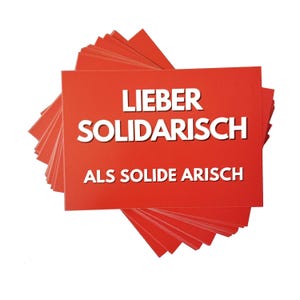 Könnte beinhalten: Ein Stapel roter quadratischer Karten mit weißem Text. Der Text auf den Karten lautet "LIEBER SOLIDARISCH ALS SOLIDE ARISCH". Die Karten sind aufgefächert und zeigen die Kanten jeder Karte.