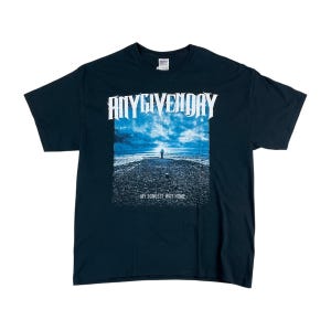 May include: A white ceramic mug with a black handle and the text "But First, Coffee" in a bold, black font. The mug is set against a blurred background, suggesting a cozy setting.