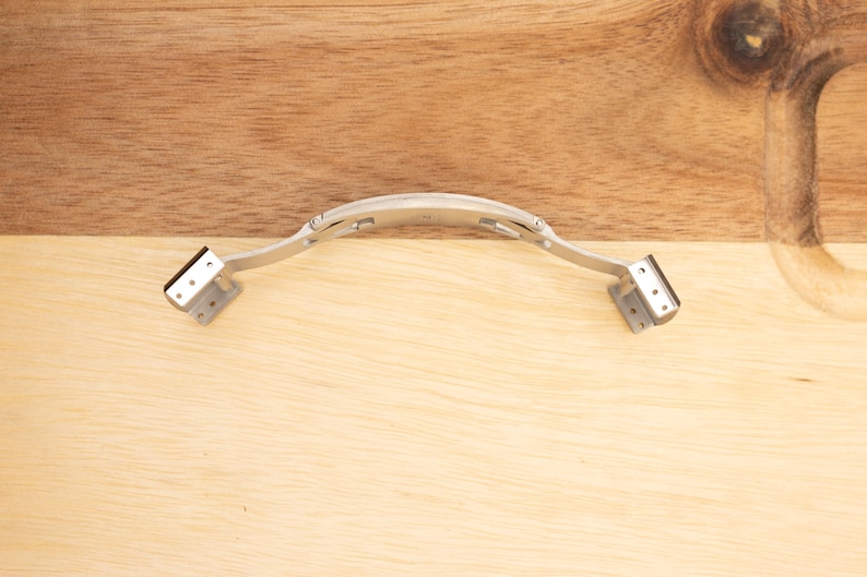 May include: A silver metal watch band clasp with a hinged design. The clasp is open and ready to be attached to a watch band.