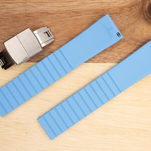 May include: Two light blue silicone watch bands with a silver watch band buckle.