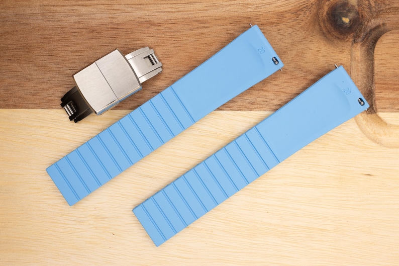 May include: Two light blue silicone watch bands with a silver watch band buckle.
