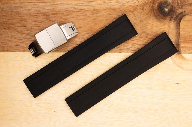 Puede incluir: Dos correas de reloj de caucho negro con una hebilla plateada. Las correas tienen una superficie texturizada y est&aacute;n dise&ntilde;adas para un reloj.