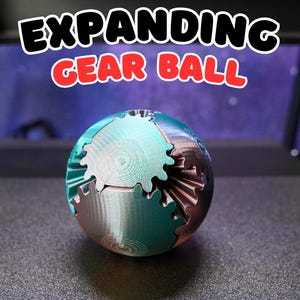May include: A multi-colored gear ball with the text "EXPANDING GEAR BALL" in a black and red font. The ball is made of interlocking gears in shades of teal, silver, and bronze. The gears are arranged to form a sphere.