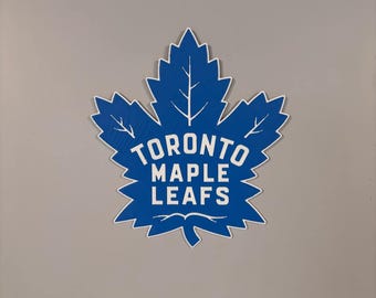 Könnte beinhalten: Ein blaues Ahornblatt mit dem Schriftzug "Toronto Maple Leafs" in weiß.