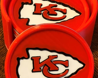 Könnte beinhalten: Ein Satz mit vier roten Untersetzern mit einem weißen und schwarzen Kansas City Chiefs Logo. Die Untersetzer sind in einem Halter gestapelt.