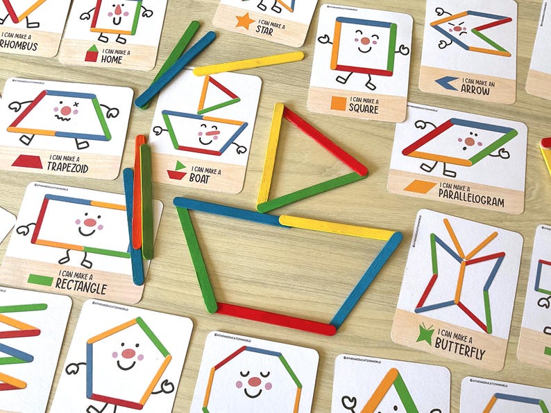 May include: A set of educational activity cards featuring colorful illustrations of shapes and objects like a boat, star, and butterfly, accompanied by wooden craft sticks in red, blue, green, and yellow, used to recreate the shapes shown on the cards.
