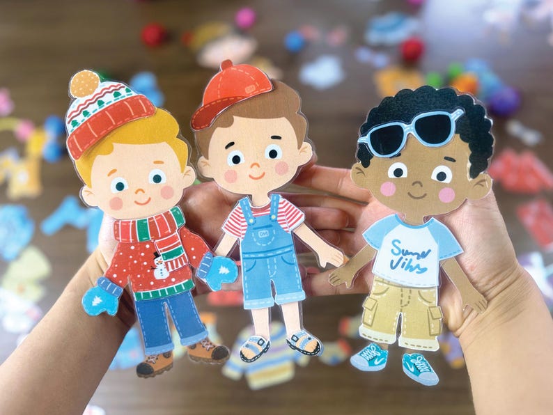 Pode incluir: Tr&ecirc;s figuras de papel com roupas diversas. A figura da esquerda usa um gorro de inverno vermelho, um su&eacute;ter com um boneco de neve e luvas azuis. A figura central usa um bon&eacute; vermelho e jardineiras azuis. A figura da direita usa &oacute;culos de sol e uma camiseta com o texto Summer Vibes.