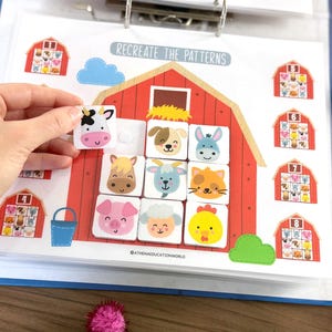 Op de afbeelding: Een educatief werkblad getiteld RECREATE THE PATTERNS met een grote rode schuurillustratie met een raster voor het plaatsen van vierkante tegels. De tegels tonen kleurrijke cartoon-dierengezichten, waaronder een koe, hond, ezel, paard, geit, kat, varken, schaap en kuiken.