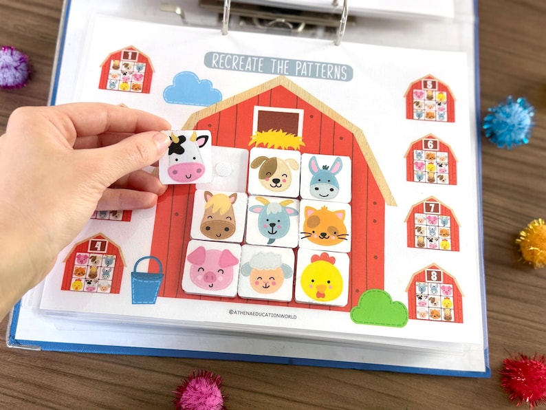 Op de afbeelding: Een educatief werkblad getiteld RECREATE THE PATTERNS met een grote rode schuurillustratie met een raster voor het plaatsen van vierkante tegels. De tegels tonen kleurrijke cartoon-dierengezichten, waaronder een koe, hond, ezel, paard, geit, kat, varken, schaap en kuiken.