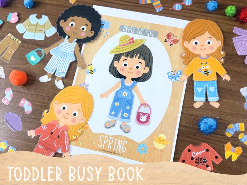 Op de afbeelding: Een papieren poppenset getiteld Dress The Girl Spring met een centraal figuur in een blauwe tuinbroek met madeliefjesprint, een strooien hoed en een roze tas, omringd door extra papieren poppen en diverse kledingstukken zoals truien, broeken en sokken.