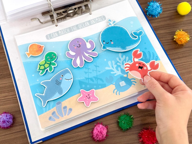 Op de afbeelding: Een educatieve activiteitenpagina getiteld I CAN MATCH THE OCEAN ANIMALS met cartoon-uitsparingen van een walvis, octopus, schildpad, krab, zeester en vis op een blauwe achtergrond met een zandbodem, koraal en een gezonken schip.