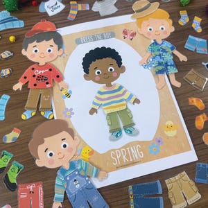 Pode incluir: Um conjunto de bonecos de papel intitulado Dress The Boy Spring com uma personagem central vestindo um su&eacute;ter listrado e cal&ccedil;as cargo verdes, rodeado por v&aacute;rios itens de vestu&aacute;rio intercambi&aacute;veis como chap&eacute;us, camisas, cal&ccedil;as e sapatos.