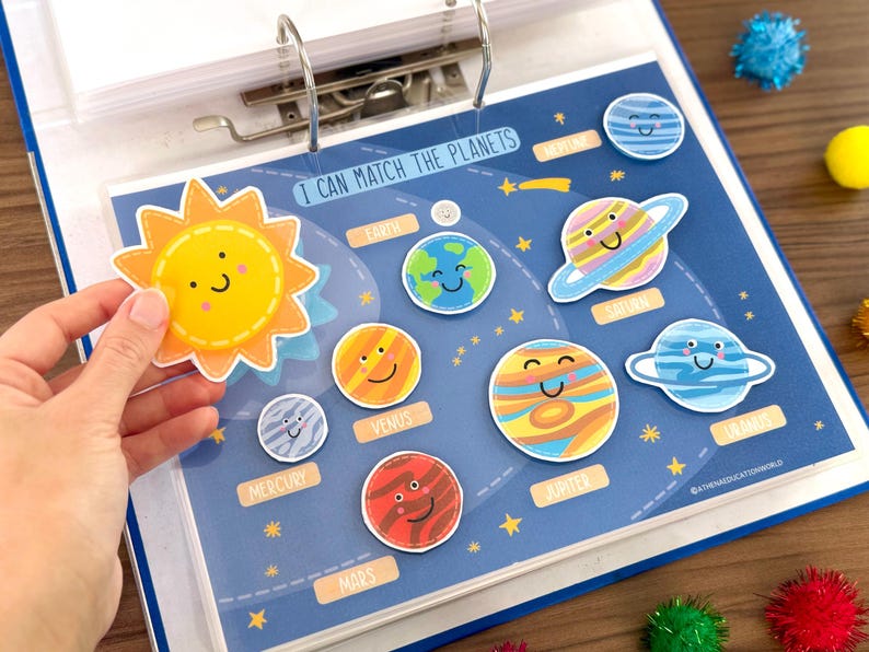 Op de afbeelding: Een educatief activiteitenblad getiteld I CAN MATCH THE PLANETS met een donkerblauwe achtergrond en gele sterren. Het bevat uitgesneden illustraties van de zon en planeten, elk met een lachend gezicht, om te matchen met de gelabelde plekken.