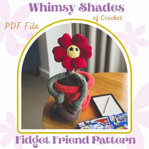 May include: A crocheted flower with a red flower head, yellow center, and green stem sits in a red and brown pot. The image includes the text "Whimsy Shades of Crochet" and "Fidget Friend Pattern".