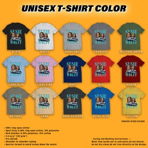 May include: A mockup of a unisex t-shirt featuring a graphic of two women with the text "Susie Wolff" in a blue font. The t-shirt is shown in 12 different colors: black, white, sport grey, charcoal, military green, light blue, light pink, navy, red, maroon, natural, sand, dark heather, royal blue, and yellow. The text "Provide other colors" is at the bottom of the image.