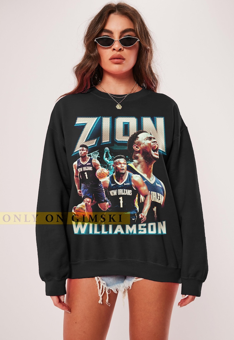 May include: Black sweatshirt featuring a graphic of Zion Williamson in a New Orleans Pelicans jersey. The design includes the name "ZION" in large, stylized letters and the name "WILLIAMSON" below. The text "ONLY ON GIMSKI" is also visible.
