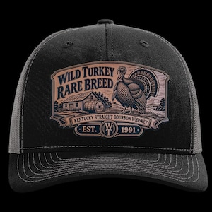 May include: A black baseball cap featuring a rectangular patch with a graphic of a wild turkey, a wooden barrel, and a barn. The text reads Wild Turkey Rare Breed, Kentucky Straight Bourbon Whiskey, and Est. 1991 with a central WT logo emblem.