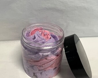 May include: A clear glass jar with a black lid filled with a swirl of purple and pink whipped body butter.