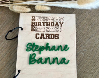 May include: A wooden scrapbook with a brown inscription that reads "Birthday Cards" and "1978 and on..."  The scrapbook has a green inscription that reads "Stephane Banna".