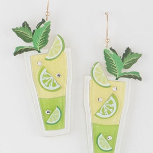 Op de afbeelding: Een paar limoengroene en gele oorhangers in de vorm van een glas limonade met een limoenwig en een muntversiering.