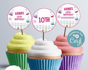 May include: Three cupcakes with different colored frosting and cupcake liners. Each cupcake has a round, white and pink circle topper with a science theme. The toppers have text that says "Kayla's 10th Birthday" and "10th".