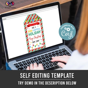 May include: A laptop screen displaying a Christmas gift tag template with the text "Have a DOH Lightful Holiday Merry Christmas! From: Sonny". The text is in a colorful font with red and green stripes. The template is customizable with the Corjl software.