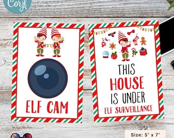 May include: Two printable signs for Christmas featuring elves. The first sign has a camera with the text "Elf Cam". The second sign has an elf with the text "This house is under elf surveillance". Both signs have a red and green striped background.