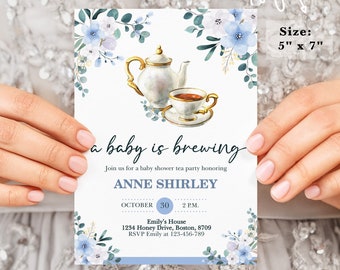 May include: A baby shower invitation with a blue and white watercolor floral design. The invitation features a teapot and teacup with the text "a baby is brewing". The invitation is for Anne Shirley and is scheduled for October 30th at 2 p.m. at Emily's House. The address and RSVP information are included on the invitation.