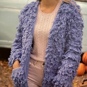 May include: A light blue fuzzy cardigan with a long sleeve and a pocket on the left side.