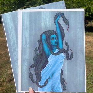 May include: A blue-skinned woman with long, dark hair and a white dress is surrounded by snakes. The snakes are green and have yellow eyes. The background is a light blue with a hazy, forest-like pattern.