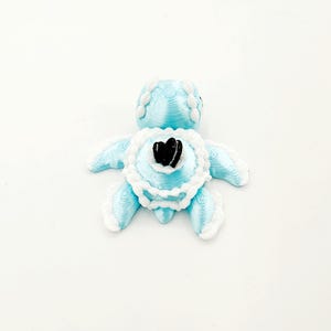 May include: A blue and white turtle cake topper with a black and white cookie on top.