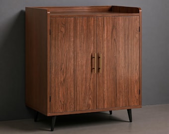 May include: A rectangular wooden cabinet with a rich brown wood grain finish, featuring two doors with vertical brass-toned handles. The cabinet is supported by four tapered black legs and includes a raised edge along the top surface.