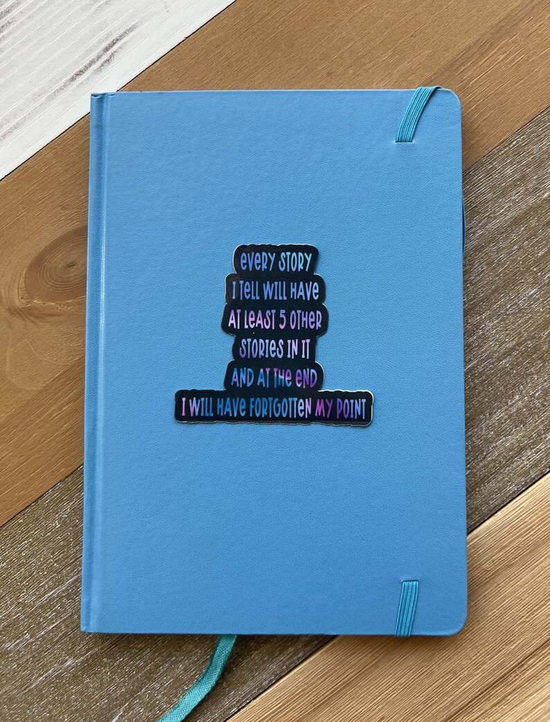 Puede incluir: Un cuaderno azul con una pegatina que dice "Cada historia que cuento tendr&aacute; al menos 5 historias m&aacute;s en ella y al final me habr&eacute; olvidado de mi punto."