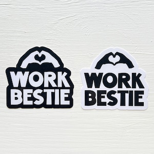 May include: Two stickers with the text "Work bestie" in white letters on a black and white background. The stickers feature a heart shape made with hands.