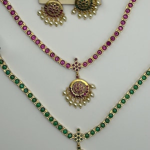 May include: Gold-toned jewelry set featuring necklaces and earrings. The necklaces have a series of round gemstones in pink and green, with matching pendant earrings. The earrings and pendants have a floral design with small pearls.