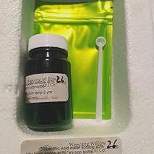 May include: A dark green glass bottle with a white lid and a label, a small white spoon, and a bright yellow pouch are in a white container. The label reads "Weeping Willow" and other text. A second label is below.